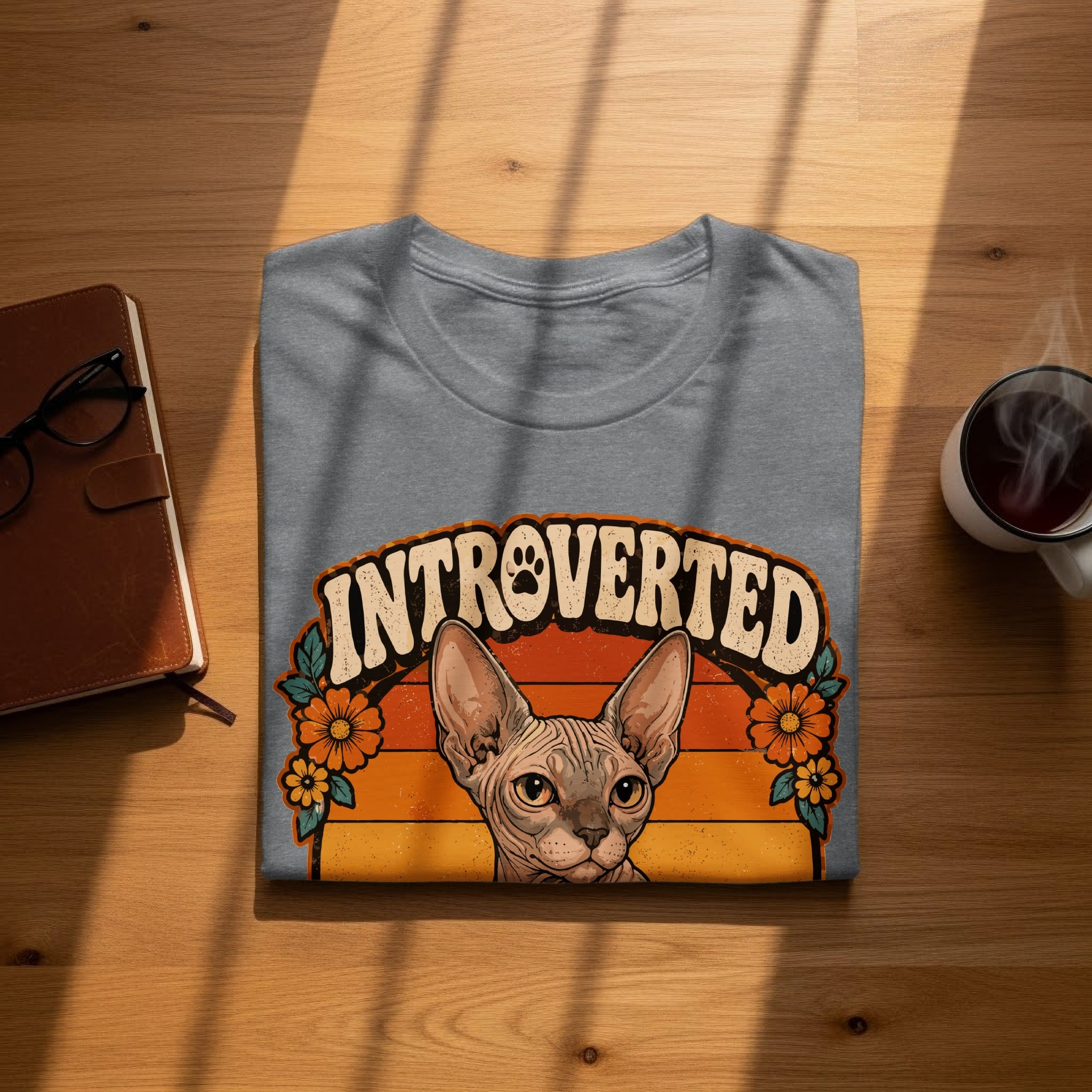 Sphynx cat wearing a floral crown on a grey t-shirt with text INTROVERTED.