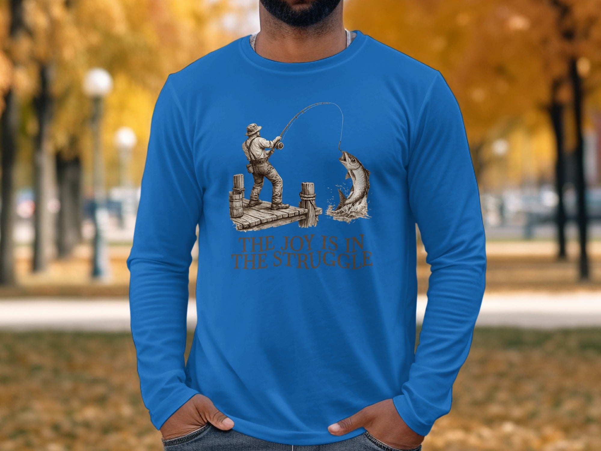 Man wearing blue t-shirt with fisherman reeling in a large fish.