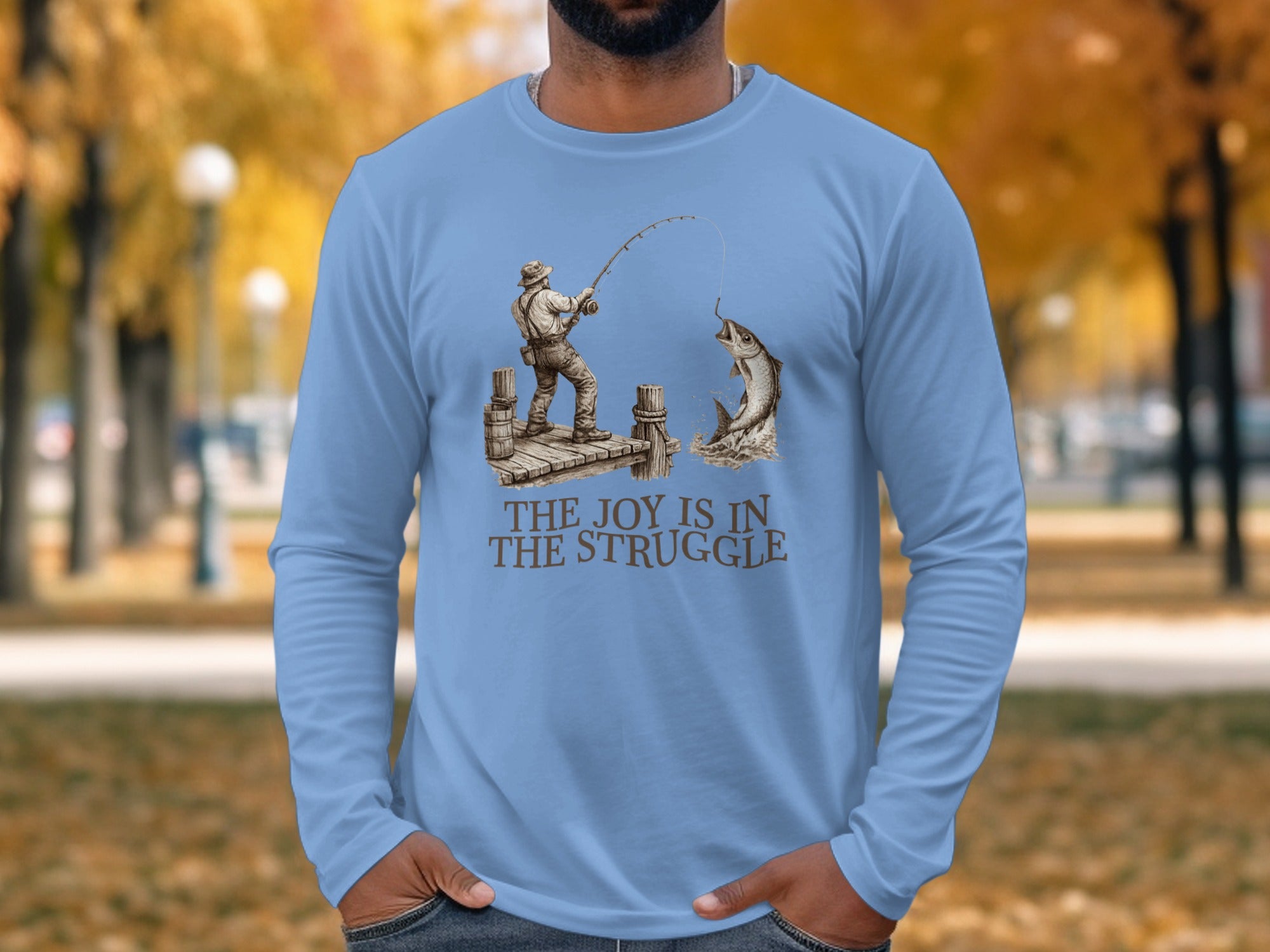 Man wearing light blue long-sleeve t-shirt with fishing graphic and text.