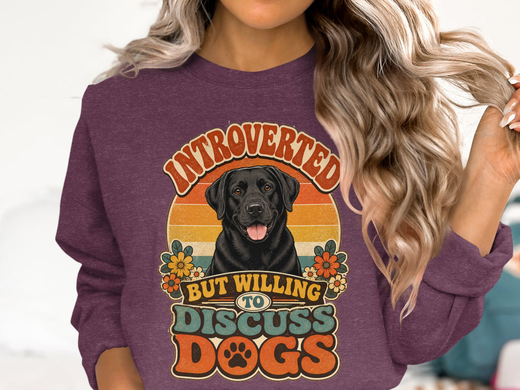 Black lab with flowers on a maroon sweatshirt that reads "Introverted but willing to discuss dogs."