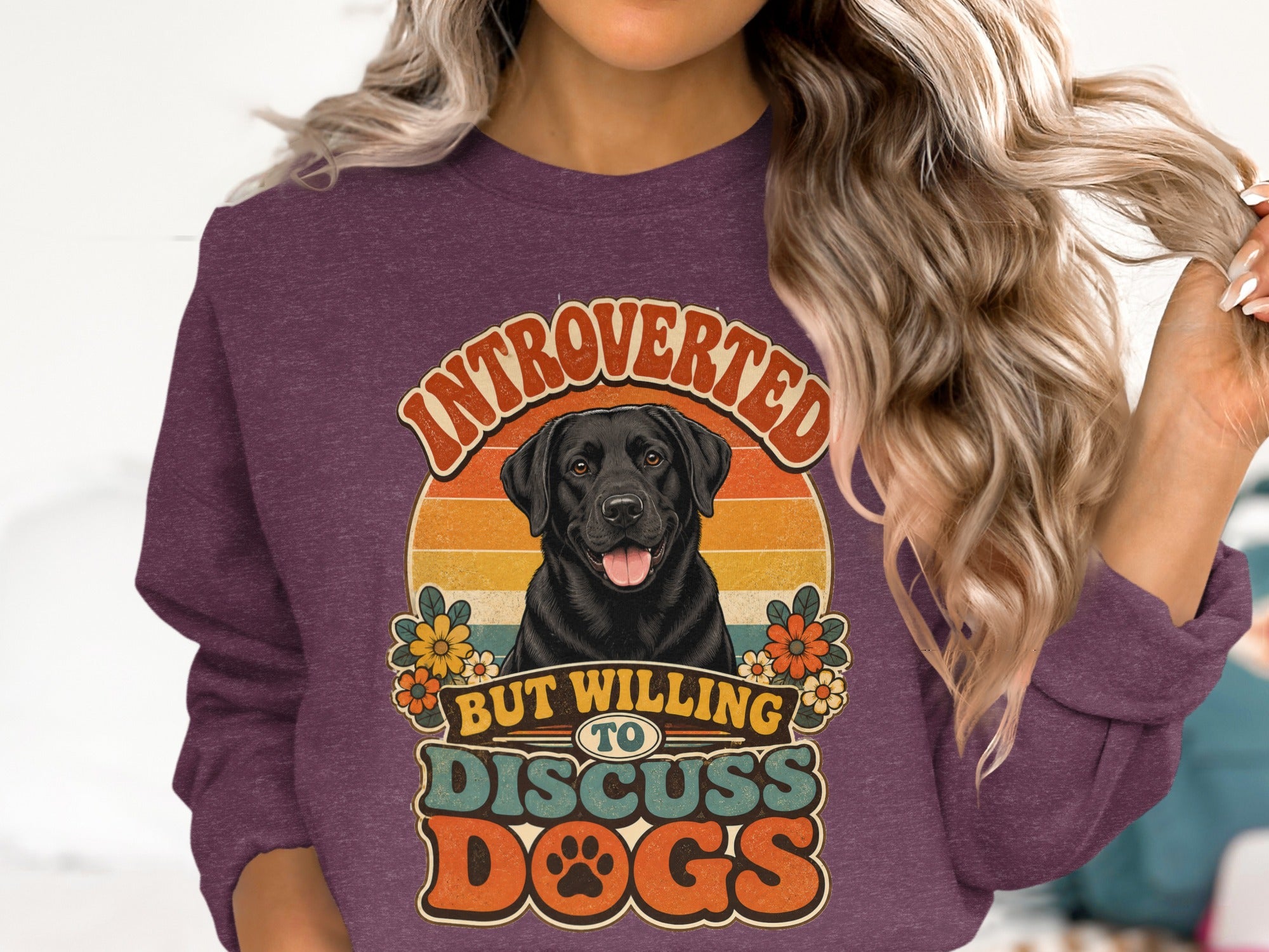 Black lab with flowers on a maroon sweatshirt that reads "Introverted but willing to discuss dogs."
