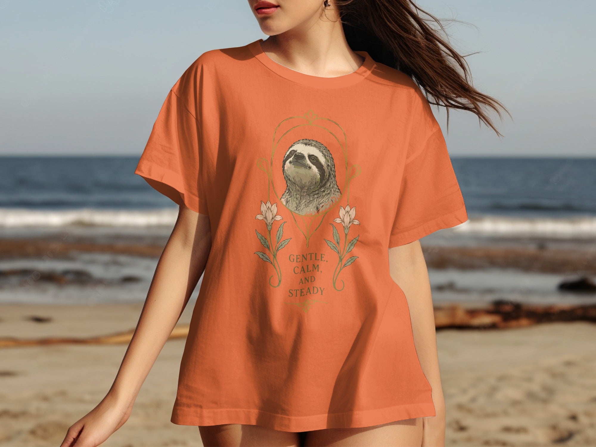 Orange t-shirt with sloth, flowers, and text "GENTLE, CALM AND STEADY".