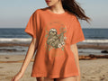 Orange t-shirt with sloth, flowers, and "THE SWEET LIFE" text in a circular emblem.